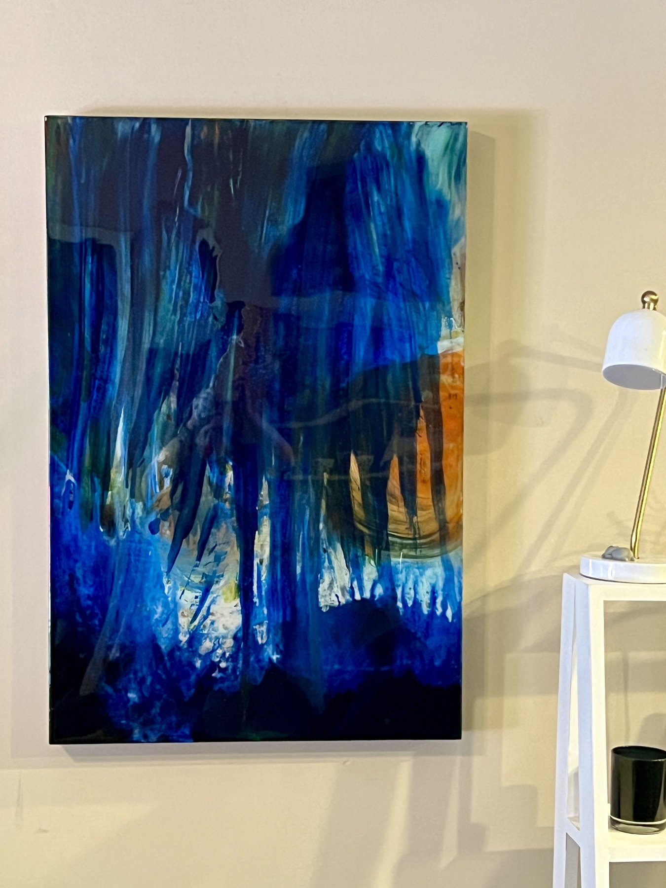 Blue abstract painting displayed beside a lamp